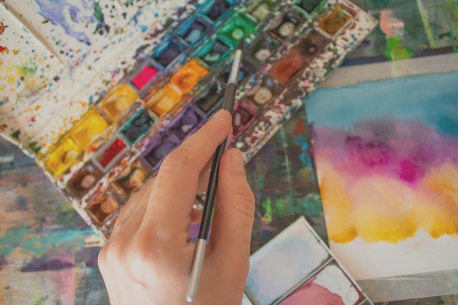 Studente che pratica tecniche di acquerello durante una sessione di laboratorio creativo